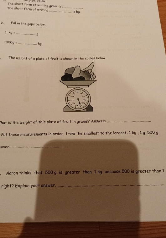 gups below. 
The short form of writing gram is_ 
The short form of writing _is kg. 
2. Fill in the gaps below.
1kg= _ 9
1000g= _ kg
The weight of a plate of fruit is shown in the scales below. 
What is the weight of this plate of fruit in grams? Answer:_ 
Put these measurements in order, from the smallest to the largest: 1 kg , 1 g, 500 g
swer:_ 
. Aaron thinks that 500 g is greater than 1 kg because 500 is greater than 1
right? Explain your answer. 
_