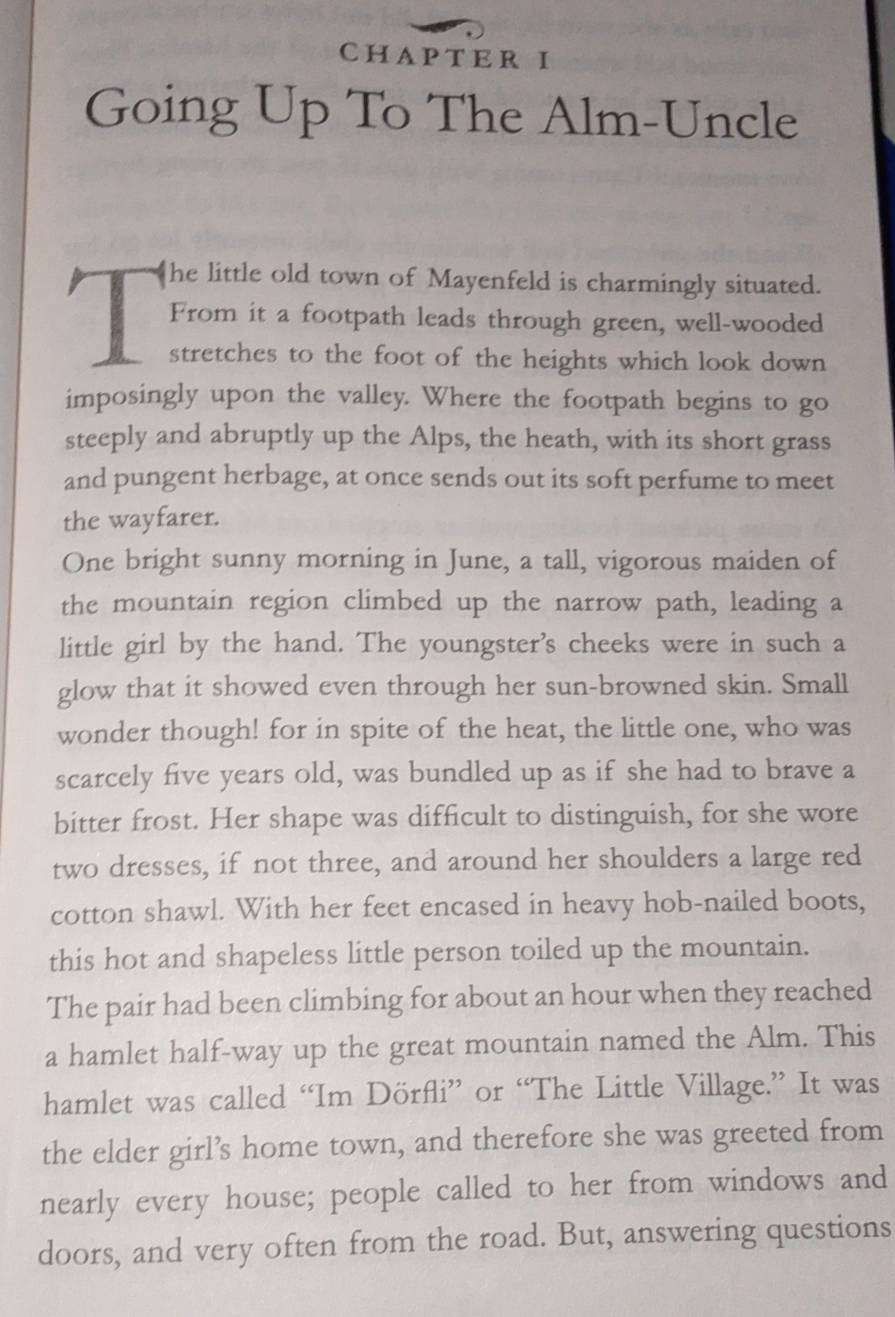 CHAPTER I 
Going Up To The Alm-Uncle 
he little old town of Mayenfeld is charmingly situated. 
From it a footpath leads through green, well-wooded 
1 stretches to the foot of the heights which look down 
imposingly upon the valley. Where the footpath begins to go 
steeply and abruptly up the Alps, the heath, with its short grass 
and pungent herbage, at once sends out its soft perfume to meet 
the wayfarer. 
One bright sunny morning in June, a tall, vigorous maiden of 
the mountain region climbed up the narrow path, leading a 
little girl by the hand. The youngster’s cheeks were in such a 
glow that it showed even through her sun-browned skin. Small 
wonder though! for in spite of the heat, the little one, who was 
scarcely five years old, was bundled up as if she had to brave a 
bitter frost. Her shape was difficult to distinguish, for she wore 
two dresses, if not three, and around her shoulders a large red 
cotton shawl. With her feet encased in heavy hob-nailed boots, 
this hot and shapeless little person toiled up the mountain. 
The pair had been climbing for about an hour when they reached 
a hamlet half-way up the great mountain named the Alm. This 
hamlet was called “Im Dörfli” or “The Little Village.” It was 
the elder girl’s home town, and therefore she was greeted from 
nearly every house; people called to her from windows and 
doors, and very often from the road. But, answering questions