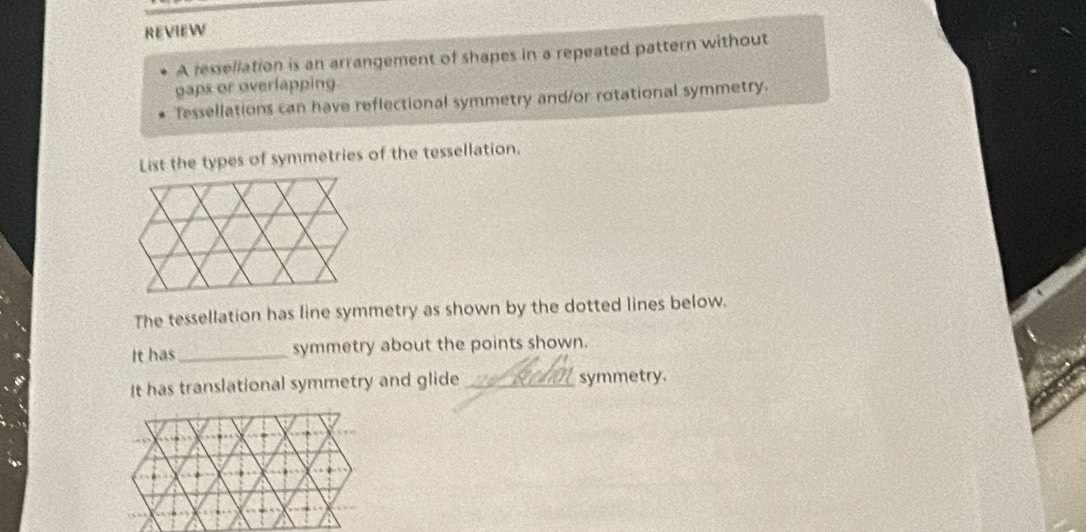 REVIEW 
A ressellation is an arrangement of shapes in a repeated pattern without 
gaps or overlapping. 
Tessellations can have reflectional symmetry and/or rotational symmetry. 
List the types of symmetries of the tessellation. 
The tessellation has line symmetry as shown by the dotted lines below. 
It has_ symmetry about the points shown. 
It has translational symmetry and glide _symmetry.