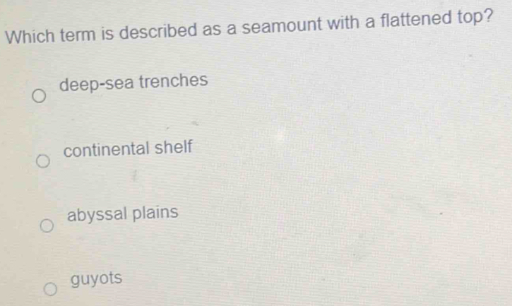 Which term is described as a seamount with a flattened top?
deep-sea trenches
continental shelf
abyssal plains
guyots