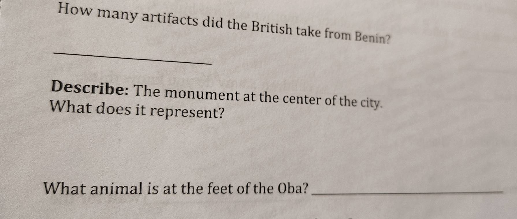 How many artifacts did the British take from Benin? 
_ 
Describe: The monument at the center of the city. 
What does it represent? 
What animal is at the feet of the Oba?_