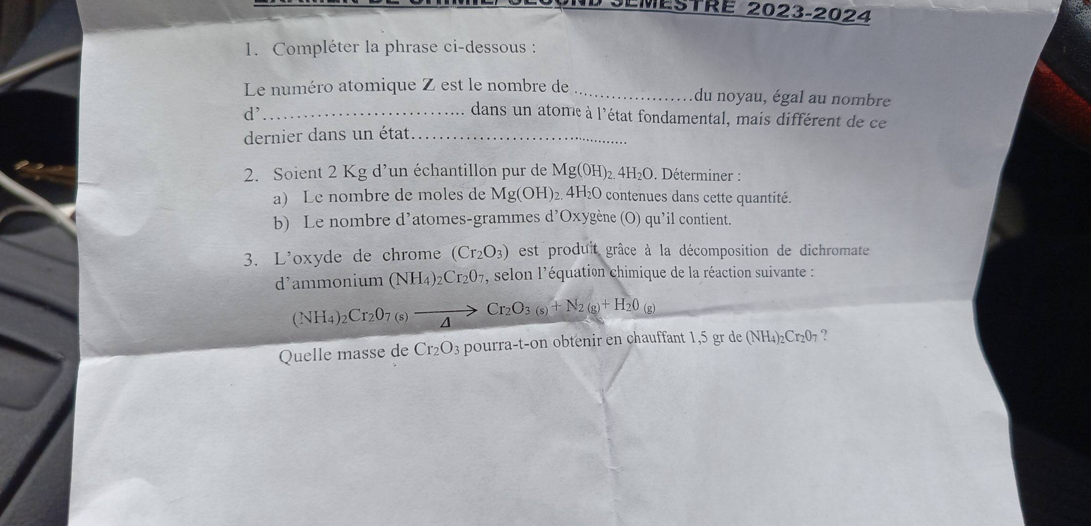 SEMESTRE 2023-2024 
1. Compléter la phrase ci-dessous : 
Le numéro atomique Z est le nombre de _du noyau, égal au nombre
d^, _ dans un atome à l'état fondamental, mais différent de ce 
dernier dans un état_ 
2. Soient 2 Kg d’un échantillon pur de Mg(OH)_2.4H_2O. Déterminer : 
a) Le nombre de moles de Mg(OH)_2 4 H_2O contenues dans cette quantité. 
b) Le nombre d’atomes-grammes d’Oxygène (O) qu’il contient. 
3. L'oxyde de chrome (Cr_2O_3) est produit grâce à la décomposition de dichromate 
d’ammonium (NH_4)_2Cr_2O_7 , selon l'équation chimique de la réaction suivante :
(NH_4)_2Cr_2O_7(s)to Cr_2O_3(s)+N_2(g)+H_2O_(g)
Quelle masse de Cr_2O_3 pourra-t-on obtenir en chauffant 1,5 gr de (NH_4)_2Cr_2O_7 ?