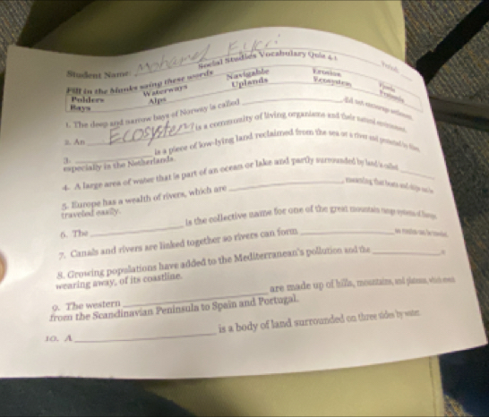 Social Studiés Vocabulary Quía 41 
Vish 
Student Name 
_ 
Fill in the banks saing these words Navigable L n tn 
Bays Polders Waterway Uplands 
_ 
Frosydra Vyorla 
The deep and namow bays of Norway is caled Alps 
is a commmsity of living organiants and their tnol emo 
ii. An _is a piece of low-lying land reclaimed from the sea or a rive sd pesned by fie 
3 
_ 
==pecially in the Notherlands 
4. A large area of witer that is part of an ocean or lake and partly surcounded by laid 's ollo 
, mening hat bot an dige ash 
5. Europe has a wealth of rivers, which are 
traveled easily. is the collective name for one of the great mountain moge etems d he. 
6. The 
_ 
7. Canals and rivers are linked together so rivers can form_ 

8. Growing popolations have added to the Mediterranean's pollution and the 
_ 
wearing away, of its coastline. _B 
are made up of hills, mountains, and pitess, who es 
9. The western 
from the Scandinavian Peninsula to Spain and Portugal. 
is a body of land surrounded on three sides by wate . 
10. A 
_