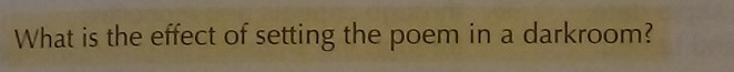 What is the effect of setting the poem in a darkroom?