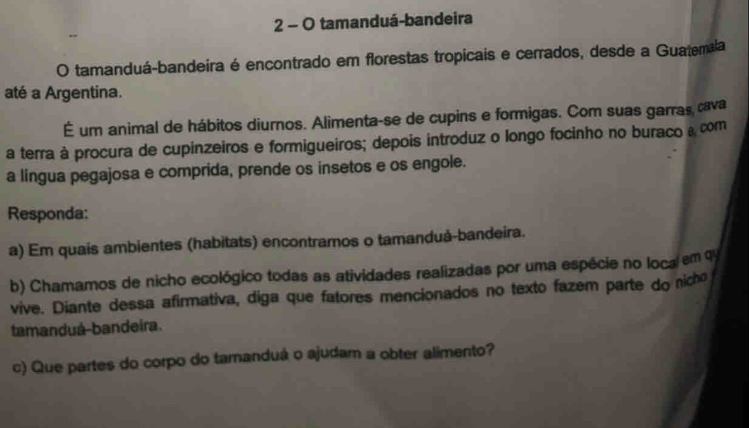 tamanduá-bandeira 
O tamanduá-bandeira é encontrado em florestas tropicais e cerrados, desde a Guatemala 
até a Argentina. 
É um animal de hábitos diurnos. Alimenta-se de cupins e formigas. Com suas garras cava 
a terra à procura de cupinzeiros e formigueiros; depois introduz o longo focinho no buraco a com 
a lingua pegajosa e comprida, prende os insetos e os engole. 
Responda: 
a) Em quais ambientes (habitats) encontramos o tamanduå-bandeira. 
b) Chamamos de nicho ecológico todas as atividades realizadas por uma espécie no loca em q 
vive. Diante dessa afirmativa, diga que fatores mencionados no texto fazem parte do nicho 
tamanduá bandeira. 
c) Que partes do corpo do tamanduá o ajudam a obter alimento?