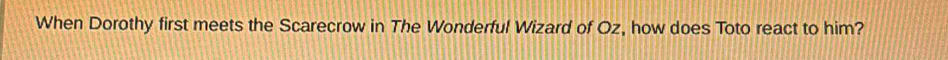 When Dorothy first meets the Scarecrow in The Wonderful Wizard of Oz, how does Toto react to him?