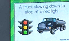 A truck slowing down to 
stop at a red light.