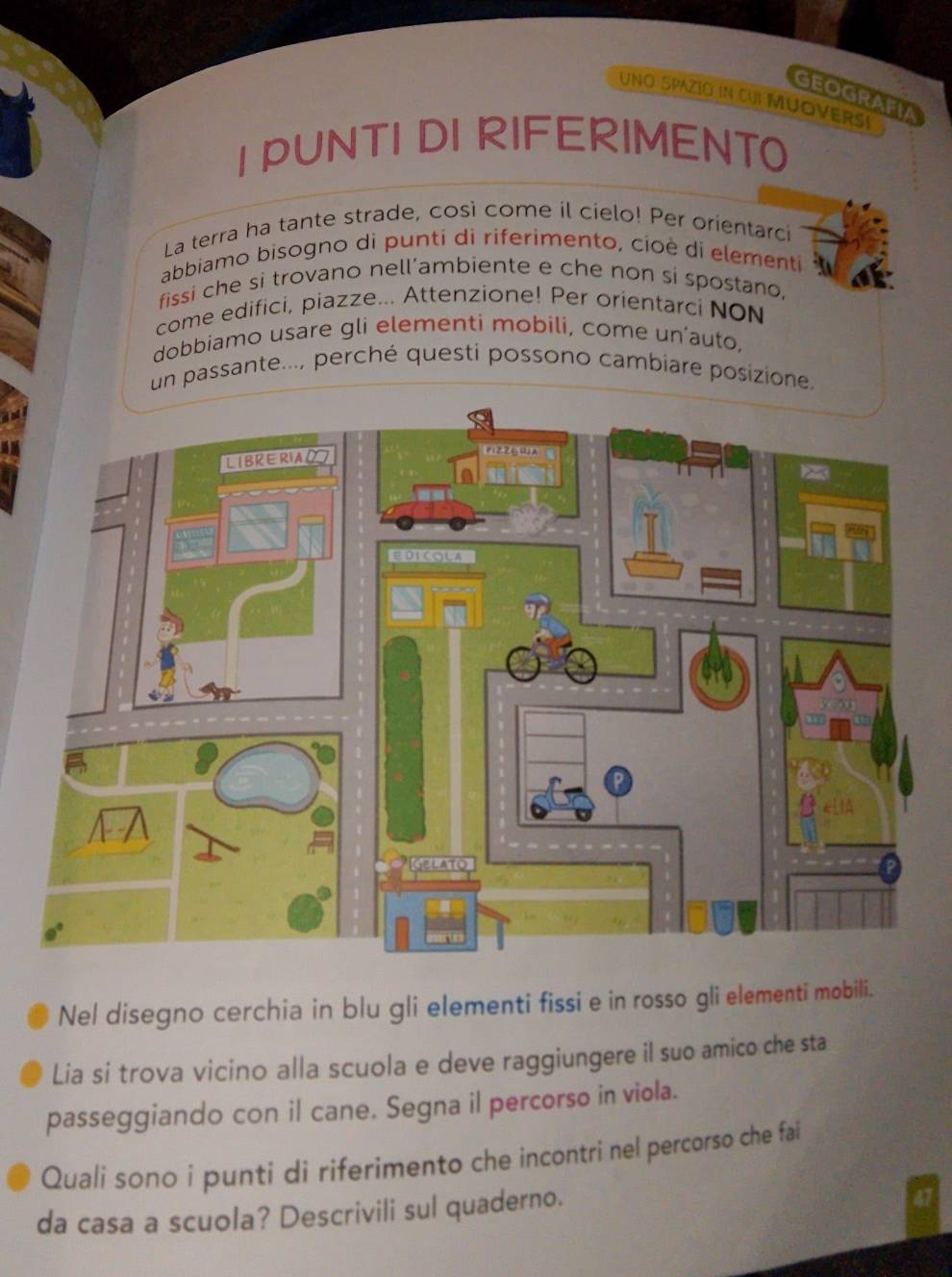 GEOGRAFIA 
UNO SPAZIO IN CUI MUOVERS! 
I PUNTI DI RIFERIMENTO 
La terra ha tante strade, così come il cielo! Per orientarci 
abbiamo bisogno di punti di riferimento, cioè di elementi 
fissi che si trovano nell’ambiente e che non si spostano, 
come edifici, piazze... Attenzione! Per orientarci NON 
dobbiamo usare gli elementi mobili, come un’auto, 
un passante..., perché questi possono cambiare posizione, 
Nel disegno cerchia in blu gli elementi fissi e in rosso gli elementi mobili. 
Lia si trova vicino alla scuola e deve raggiungere il suo amico che sta 
passeggiando con il cane. Segna il percorso in viola. 
Quali sono i punti di riferimento che incontri nel percorso che fai 
da casa a scuola? Descrivili sul quaderno.