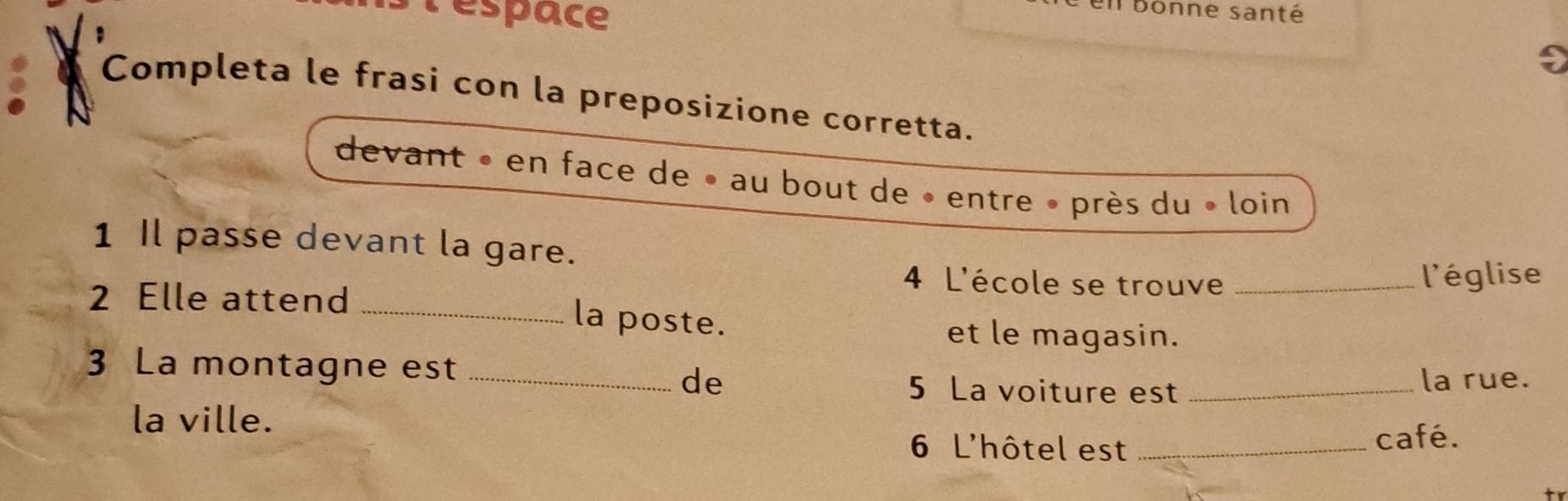 lespace 
bonne santé 
Completa le frasi con la preposizione corretta. 
. 
devant « en face de » au bout de • entre » près du « loin 
1 Il passe devant la gare. 
4 L'école se trouve _l'église 
2 Elle attend_ 
la poste. et le magasin. 
3 La montagne est_ 
de _la rue. 
5 La voiture est 
la ville. 
6 L'hôtel est _café.