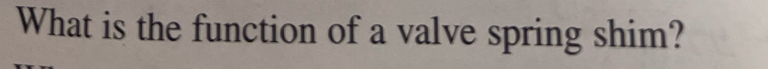 What is the function of a valve spring shim?