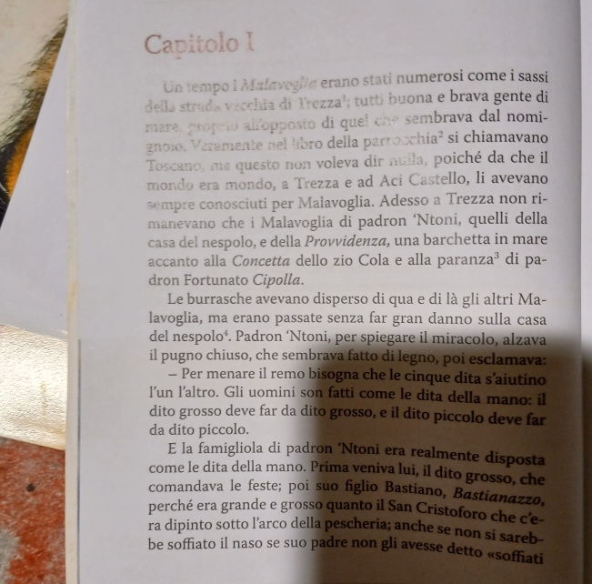 Capitolo I
Un tempo i Malaveglia erano stati numerosi come i sassi
della strada vecchia di Trezza¹; tuttí buona e brava gente di
mare, propeto alíopposto di quel che sembrava dal nomi-
gnolo. Veramente nel libro della parrocchia² si chiamavano
Toscano, ma questo non voleva dir nulla, poiché da che il
mondo era mondo, a Trezza e ad Ací Castello, li avevano
sempre conosciuti per Malavoglia. Adesso a Trezza non ri-
manevano che i Malavoglia di padron ‘Ntoni, quelli della
casa del nespolo, e della Provvidenza, una barchetta in mare
accanto alla Concettã dello zio Cola e alla paranza³ di pa-
dron Fortunato Cipolla.
Le burrasche avevano disperso di qua e di là gli altri Ma-
lavoglia, ma erano passate senza far gran danno sulla casa
del nespoloá. Padron ‘Ntoni, per spiegare il miracolo, alzava
il pugno chiuso, che sembrava fatto di legno, poi esclamava:
— Per menare il remo bisogna che le cinque dita s’aiutino
l’un l’altro. Gli uomini son fatti come le dita della mano: il
dito grosso deve far da dito grosso, e il dito piccolo deve far
da dito piccolo.
E la famigliola di padron ‘Ntoni era realmente disposta
come le dita della mano. Prima veniva lui, il dito grosso, che
comandava le feste; poi suo figlio Bastiano, Bastianazzo,
perché era grande e grosso quanto il San Cristoforo che c'e-
ra dipinto sotto l'arco della pescheria; anche se non si sareb-
be soffiato il naso se suo padre non gli avesse detto «soffiati