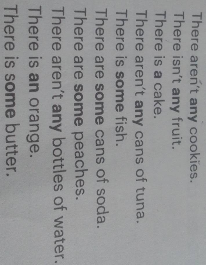 There aren't any cookies. 
There isn't any fruit. 
There is a cake. 
There aren't any cans of tuna. 
There is some fish. 
There are some cans of soda. 
There are some peaches. 
There aren't any bottles of water. 
There is an orange. 
There is some butter.