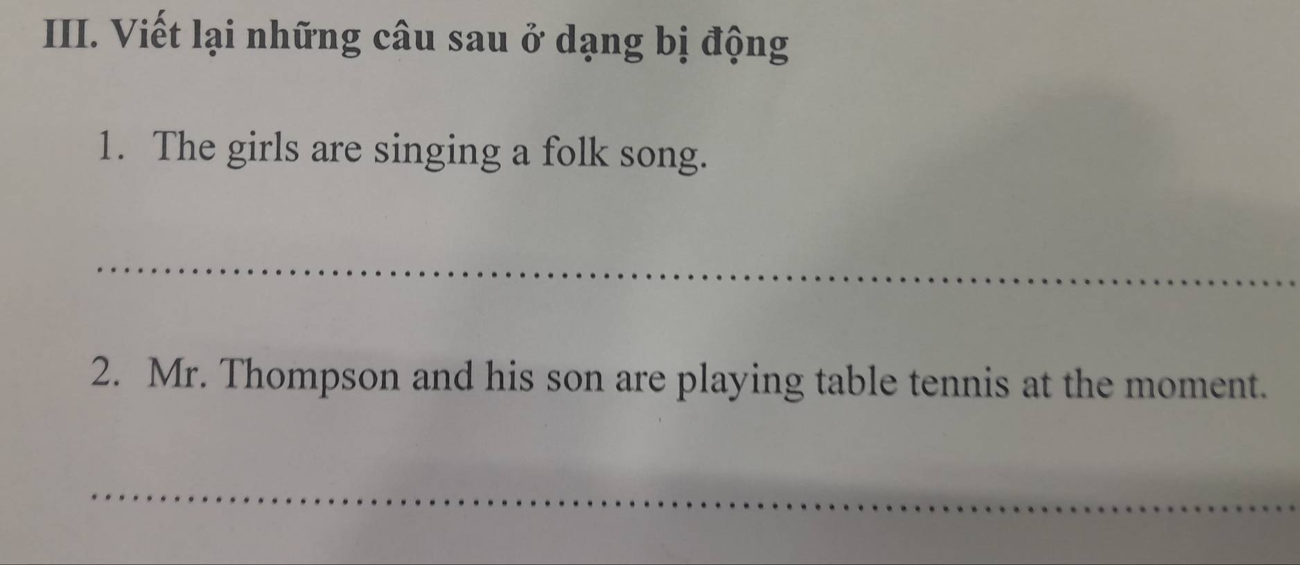 Viết lại những câu sau ở dạng bị động 
1. The girls are singing a folk song. 
_ 
2. Mr. Thompson and his son are playing table tennis at the moment. 
_