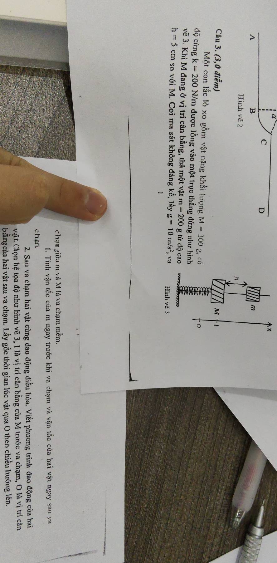 m
Hình vẽ 2
h
Câu 3. (3,0 điễm) M 
Một con lắc lò xo gồm vật nặng khối lượng M=300 g,có 
độ cứng k=200 N/m được lồng vào một trục thẳng đứng như hình 
vẽ 3. Khi M đang ở vị trí cân bằng, thả một vật m=200 g từ độ cao
h=5cm so với M. Coi ma sát không đáng 1 khat e , lấy g=10m/s^2, va Hình vẽ 3 
1 
c hạm giữa m và M là va chạm mềm. 
1. Tinh vận tốc của m ngay trước khi va chạm và vận tốc của hai vật ngay sau ya 
chạm. 
2. Sau va chạm hai vật cùng dao động điều hòa. Viết phương trình dao động của hai 
Vật. Chọn hệ tọa độ như hình vẽ 3, I là vị trí cân bằng của M trước va chạm, O là vị trí cân 
bằng của hai vật sau va chạm. Lấy gốc thời gian lúc vật qua O theo chiều hướng lên.