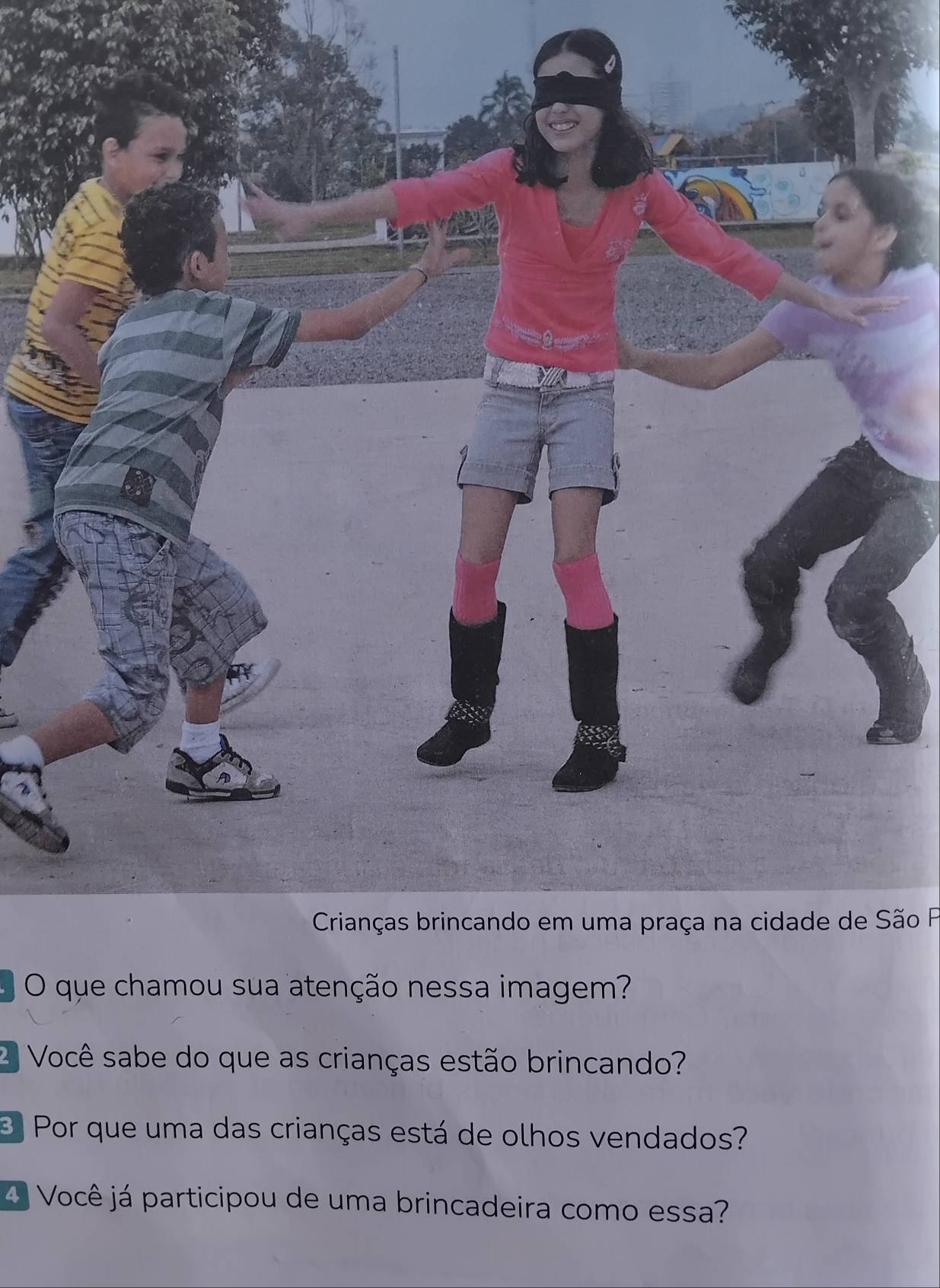 Crianças brincando em uma praça na cidade de São F 
O que chamou sua atenção nessa imagem? 
2 Você sabe do que as crianças estão brincando? 
Por que uma das crianças está de olhos vendados? 
4 Você já participou de uma brincadeira como essa?