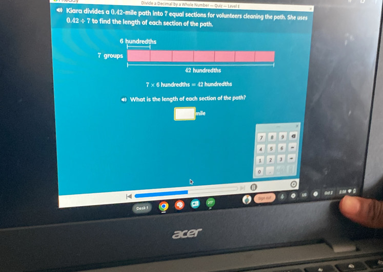 Divide a Decimal by a Whole Number — Quiz — Level E 
Kiara divides a 0.42-mile path into 7 equal sections for volunteers cleaning the path. She uses
0.42/ 7 to find the length of each section of the path.
7 × 6 hundredths =42 hundredths 
◀ What is the length of each section of the path?
□ mile
7 8 9 a
4 5 6
1 2 J
0
20 ◆ 
Desk 1