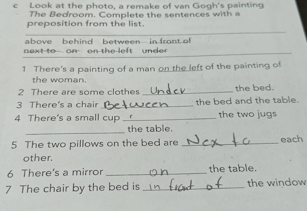 Look at the photo, a remake of van Gogh's painting 
The Bedroom. Complete the sentences with a 
preposition from the list. 
above behind between in front of 
next to on on the left under 
1 There’s a painting of a man on the left of the painting of 
the woman. 
2 There are some clothes _the bed. 
3 There's a chair _the bed and the table. 
4 There’s a small cup _the two jugs 
_ 
the table. 
5 The two pillows on the bed are_ 
each 
other. 
6 There’s a mirror _the table. 
7 The chair by the bed is _the window