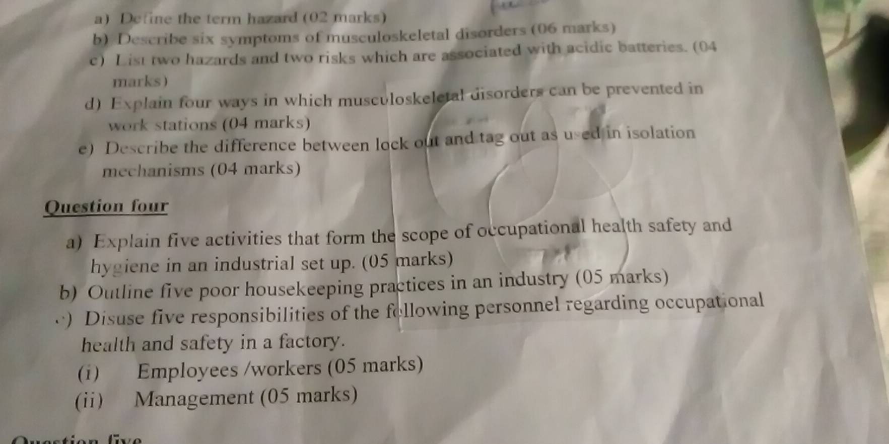 Define the term hazard (02 marks) 
b) Describe six symptoms of musculoskeletal disorders (06 marks) 
c) List two hazards and two risks which are associated with acidic batteries. (04 
marks) 
d) Explain four ways in which museuloskeletal disorders can be prevented in 
work stations (04 marks) 
e) Describe the difference between lock out and tag out as used in isolation 
mechanisms (04 marks) 
Question four 
a) Explain five activities that form the scope of occupational health safety and 
hygiene in an industrial set up. (05 marks) 
b) Outline five poor housekeeping practices in an industry (05 marks) 
c) Disuse five responsibilities of the following personnel regarding occupational 
health and safety in a factory. 
(i) Employees /workers (05 marks) 
(ii) Management (05 marks)