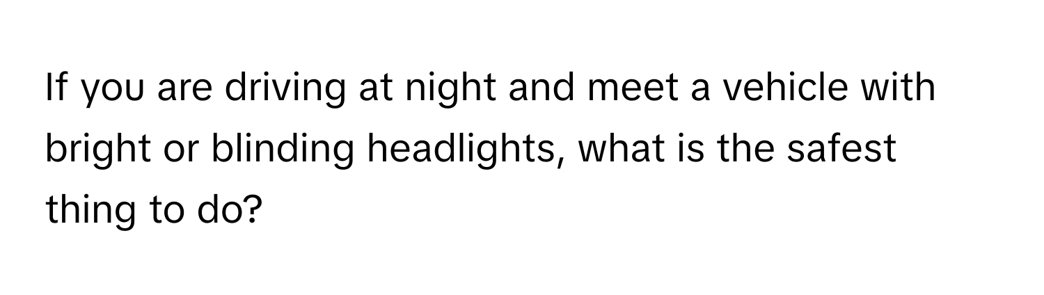 If you are driving at night and meet a vehicle with bright or blinding headlights, what is the safest thing to do?