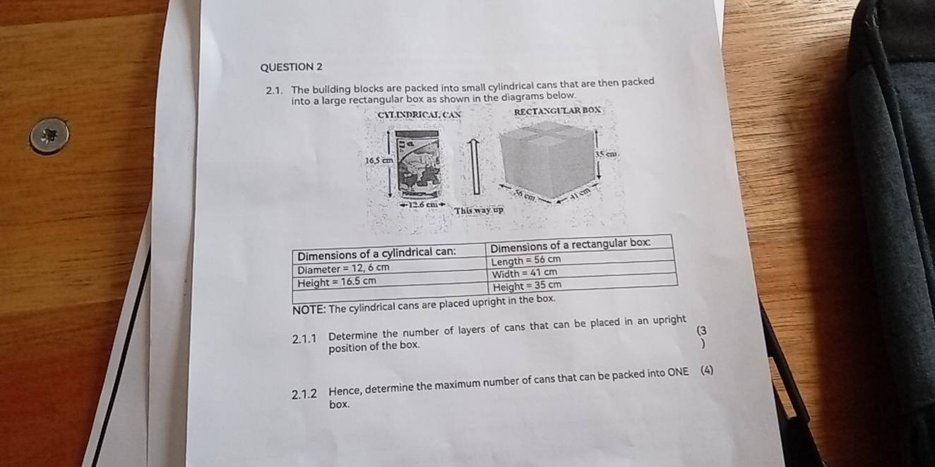 The building blocks are packed into small cylindrical cans that are then packed
into a large rectangular box as shown in the diagrams below.
CYLINDRICAL CAN RECTANGULAR BOX
+12.6 cm+
This way up
NOTE: The cylindrical cans are place
2.1.1 Determine the number of layers of cans that can be placed in an upright
(3
position of the box.
2.1.2 Hence, determine the maximum number of cans that can be packed into ONE (4)
box.