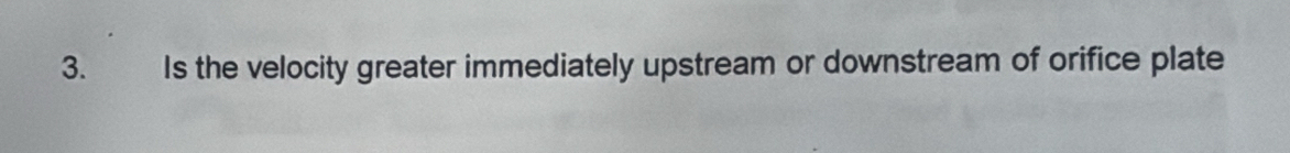 Is the velocity greater immediately upstream or downstream of orifice plate