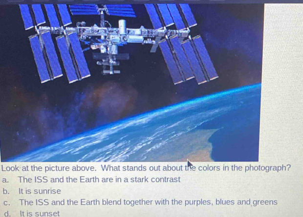 Look at the picture above. What stands out about the colors in the photograph?
a. The ISS and the Earth are in a stark contrast
b. It is sunrise
c. The ISS and the Earth blend together with the purples, blues and greens
d. It is sunset