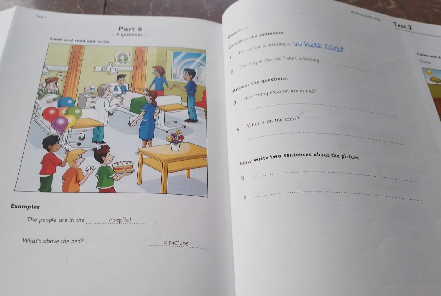 Tse 1 
Test 2 
Part 6 
= 6 questions == 
Questions 
Complete the sentences_ 
Lo 
The doctor is wearing a 
Listen and d 
2 The boy in the red T-shirt is holding_ 
Chafa 
Answer the questions. 
_ 
3 How many children are in bed? 
_ 
4 What is on the table? 
Now write two sentences about the picture. 
5 
_ 
6 
_ 
Examples 
The people are in the_ hospital_ . 
_ 
What's above the bed? _a picture