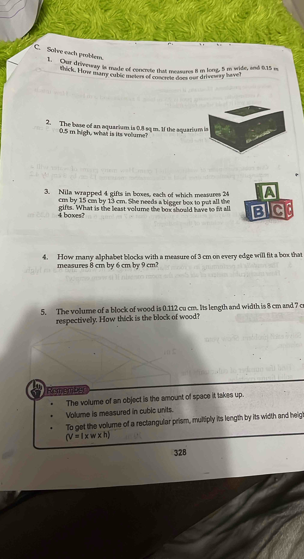 Solve each problem. 
1. Our driveway is made of concrete that measures 8 m long, 5 m wide, and 0.15 m
thick. How many cubic meters of concrete does our driveway have? 
2. The base of an aquarium is 0.8 sq m. If the aquarium is
0.5 m high, what is its volume? 
3. Nila wrapped 4 gifts in boxes, each of which measures 24
A
cm by 15 cm by 13 cm. She needs a bigger box to put all the 
gifts. What is the least volume the box should have to fit all
4 boxes? BIC 
4. How many alphabet blocks with a measure of 3 cm on every edge will fit a box that 
measures 8 cm by 6 cm by 9 cm? 
5. The volume of a block of wood is 0.112 cu cm. Its length and width is 8 cm and 7 cr
respectively. How thick is the block of wood? 
Remember 
The volume of an object is the amount of space it takes up. 
Volume is measured in cubic units. 
To get the volume of a rectangular prism, multiply its length by its width and heigl
(V=l* w* h)
328