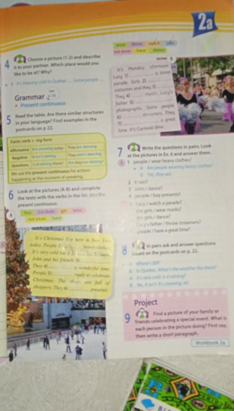 2a
w tn n t s
Choose a picture (1-2) and describe ot mew  tave  '  dace .
- .
4 it to your partner. Which place would you
like to be at? Why? It's Monday aftarmoon.
my heezing cold in Quebec ... . Some people Lucy 1) __ a strest
parade. Girts 2)
Grammar       costurers and thny 3
Present continuous Thay 40 _masks Lucy'
facther 50
5 In your language? Find examples in the 6 phstographs. Same peopie
lead the table. Are there simillar structures strowmers. They
tcards on p 22. η a qreut
ime. It's Carnoval time.
Write the questions in pairs. Look
1 at the pictures in Ex. 6 and answer them.
A) 1 people / wear heavy clothes!
* A. Are people wearing haney clatthes'
It Yes, they are
2 it rai?
Look at the pictures (A-B) and complicte 3 Johm/ dance!
the texts with the verbs in the list. Uso the 4 pinople / buy presents?
gresent continuou. S Lucy / watch a paradie
by W a skane te giels / wear masks?
mo stclee hawr sh= givls / dance ?
Lory's father / throw strearmers?
∴ cm  ;__
poople I have a great time?
='s Chrismas Ese heve in Nro 1===
a In pairs ask and anower questions
eodey, Proglr 1 g _Anary clate 8 lused on the postcands on p. 22.
's very cold bue in Iy w  he to  l m 
John and his fründs 3_
They 40 _= =omloful sim
# in Queber. What's the weatther like ohere?
Progle 5) _roguês to calaleats
A. It's very cald is it naining?
Chrisonua. Thể shrys aes full of
i  Nes, if mon't. It a snowing eto
shoppers. They & _pesms
Project
a Find a picture of your familly or
9 friends celebrating a special event. What is
each person in the picture doing? First say,
then write a short paragraph.
Workbook Za